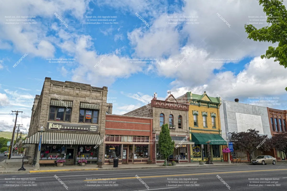 A classic view of Baker City's charming historic downtown, showing brick shopfronts, street trees, and inviting sidewalks. The nostalgic ambiance hints at local shopping, dining, and culture waiting just a short trip from the retreat.