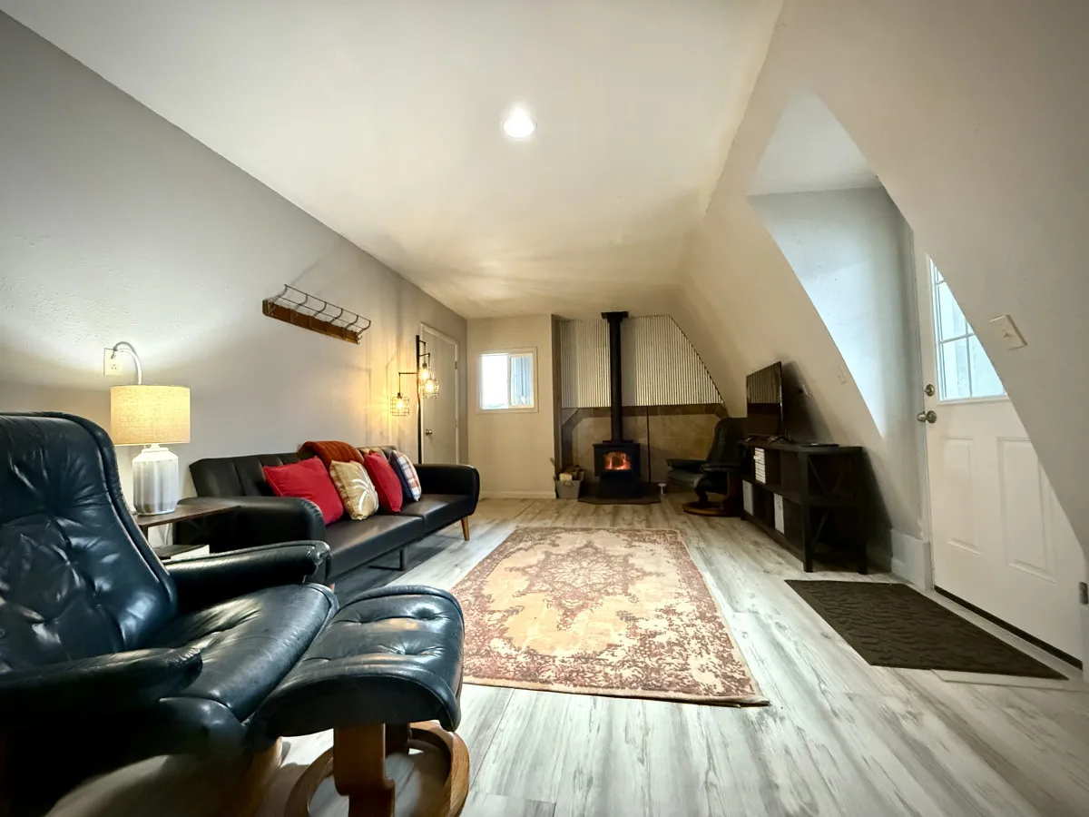 This image features a cozy interior living area with a prominent fireplace as the focal point. A comfortable sofa sits nearby atop a plush rug, with a lamp providing warm ambient light and inviting accents throughout the space.